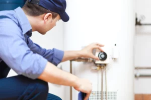 man in blue hat and uniform turning the dial on a water heater