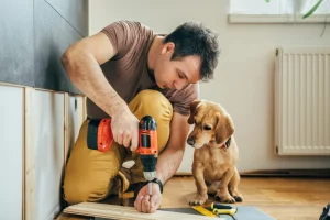 man doing renovation work at home together with his small yellow dog