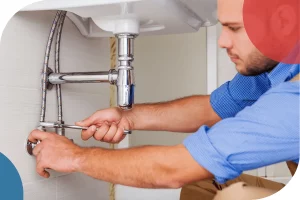 a man plumbing under a faucet wearing kakis and a blue shirt