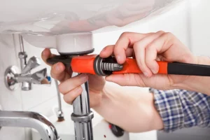 male plumber fixing a sink in a bathroom