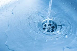 blue tinted photo of water going down the sink