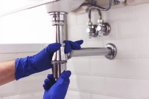 plumber using blue latex gloves under a sink